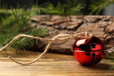 Shiny red sleigh bell on wooden table, closeup