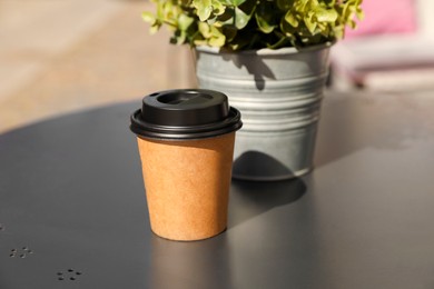 Photo of Takeaway paper cup with coffee on black outdoors