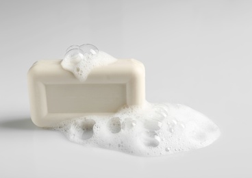 Photo of Soap bar and foam on white background