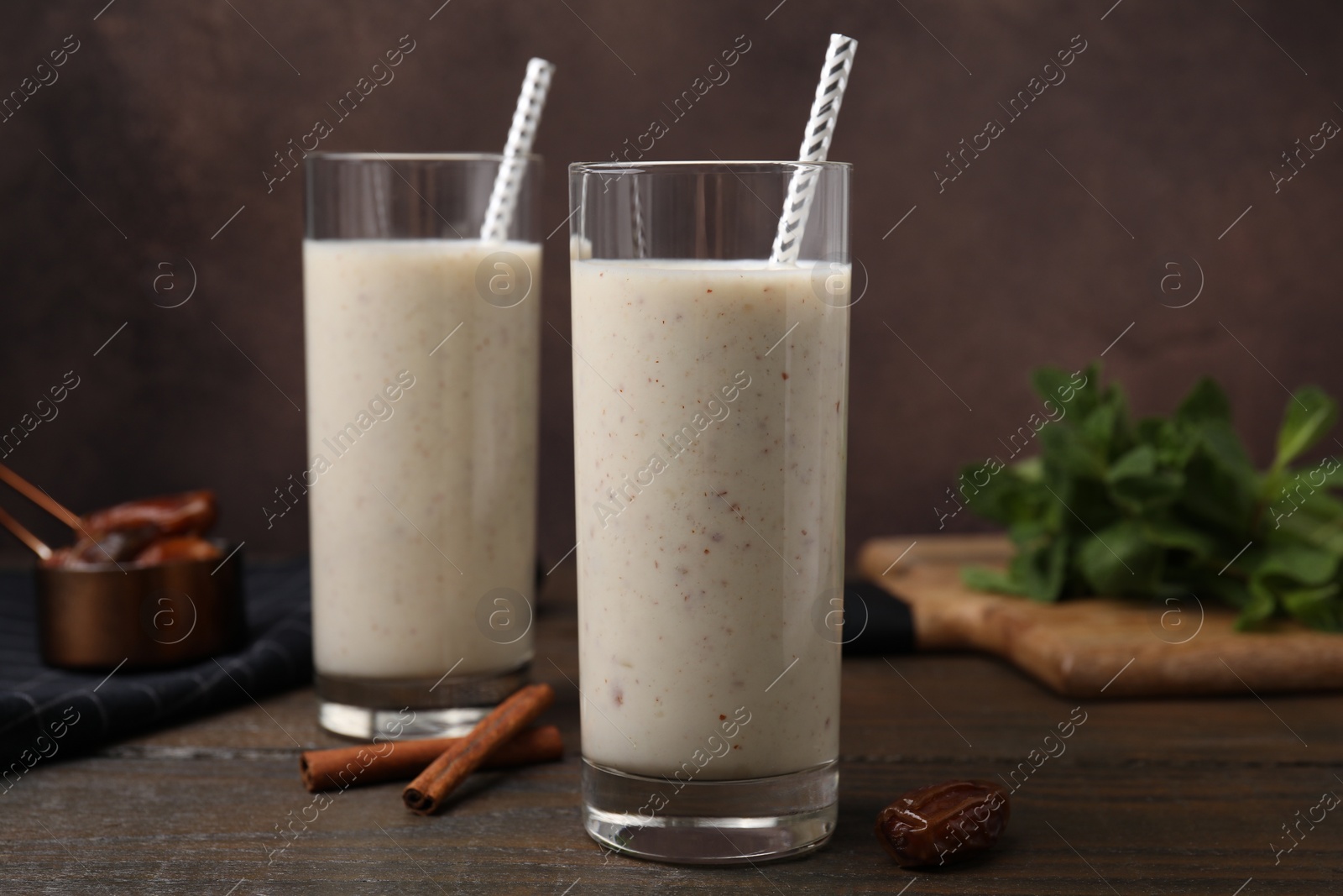 Photo of Glasses of delicious date smoothie, dried fruit and cinnamon on wooden table