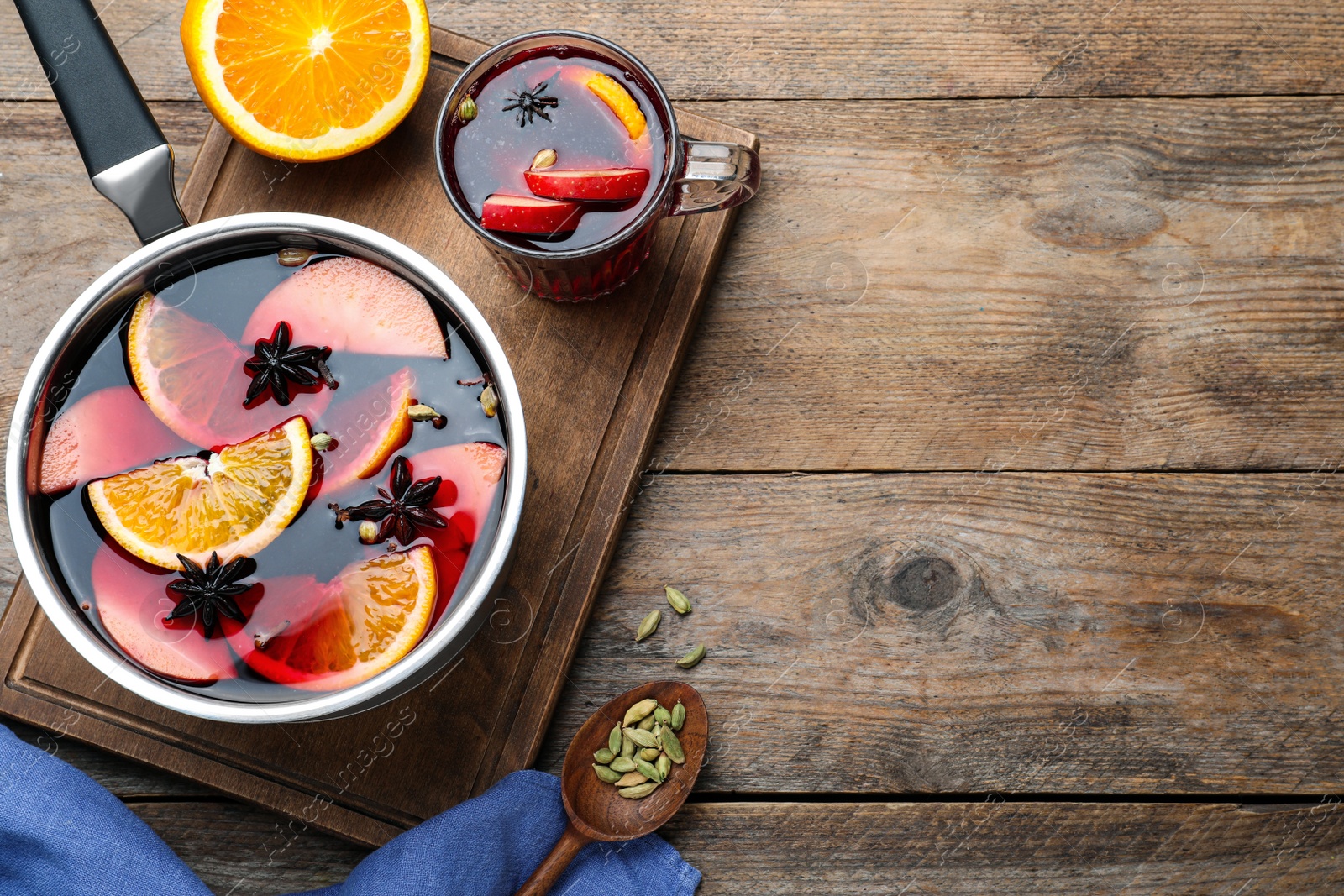 Photo of Delicious mulled wine and ingredients on wooden table, flat lay. Space for text