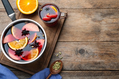 Delicious mulled wine and ingredients on wooden table, flat lay. Space for text