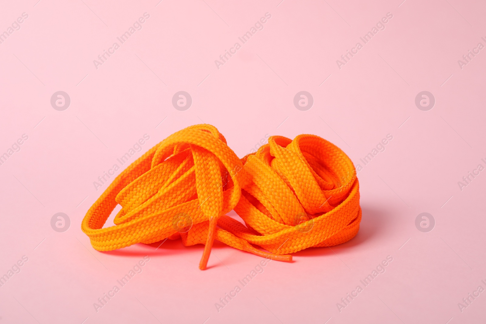 Photo of Orange shoe lace on light pink background