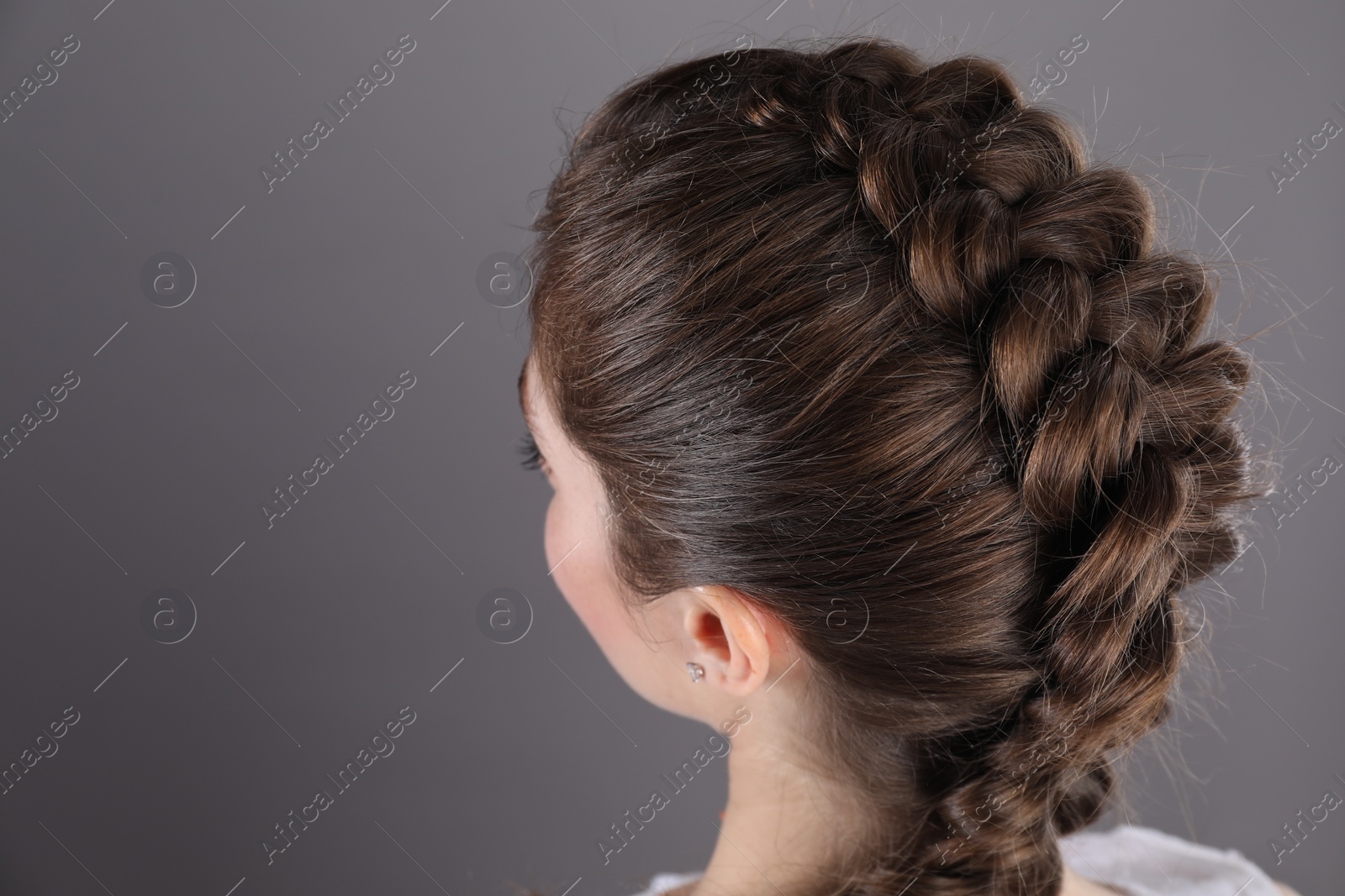 Photo of Woman with braided hair on grey background, closeup. Space for text