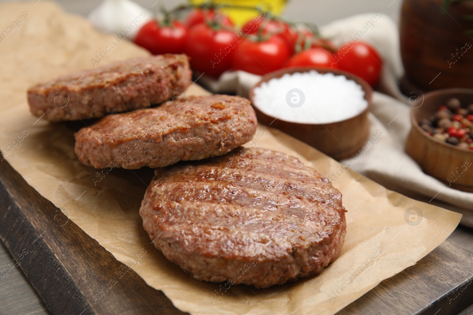 Photo of Serving board with tasty grilled hamburger patties on wooden table, closeup