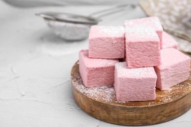 Photo of Tasty marshmallows with powder sugar on white textured table, closeup. Space for text