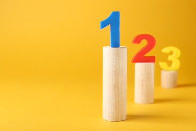 Numbers on wooden blocks against pale orange background, space for text. Competition concept