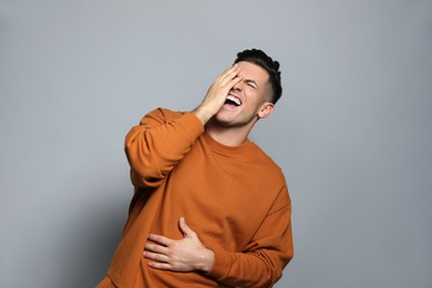 Handsome man laughing on grey background. Funny joke