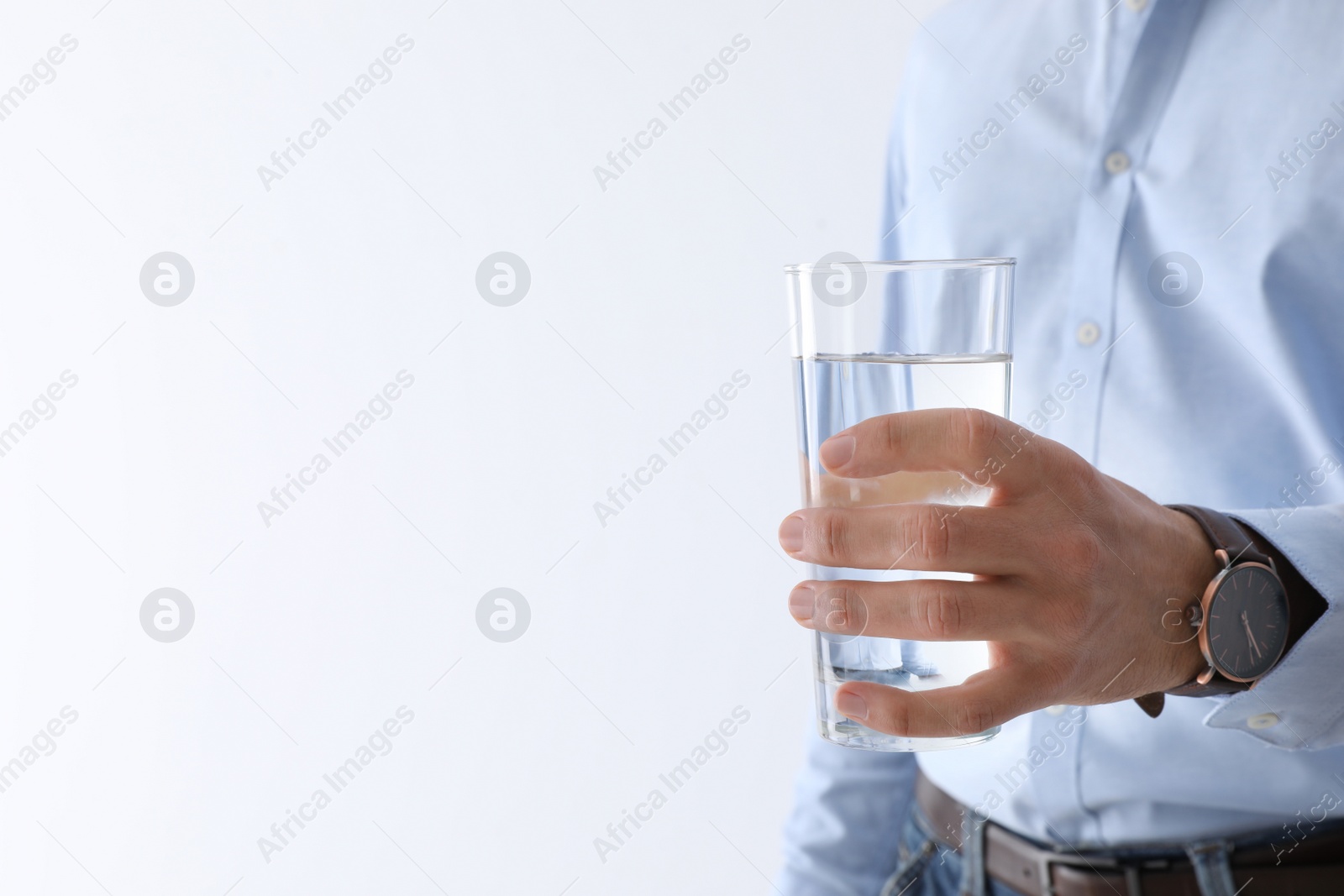 Photo of Man holding glass of pure water on white background, closeup. Space for text