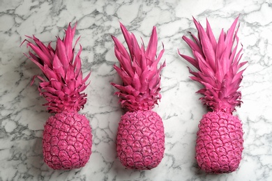 Pink pineapples on white marble background, flat lay. Creative concept