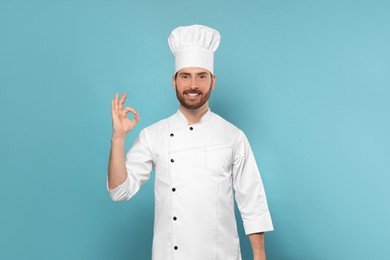 Photo of Smiling mature chef showing ok gesture on light blue background