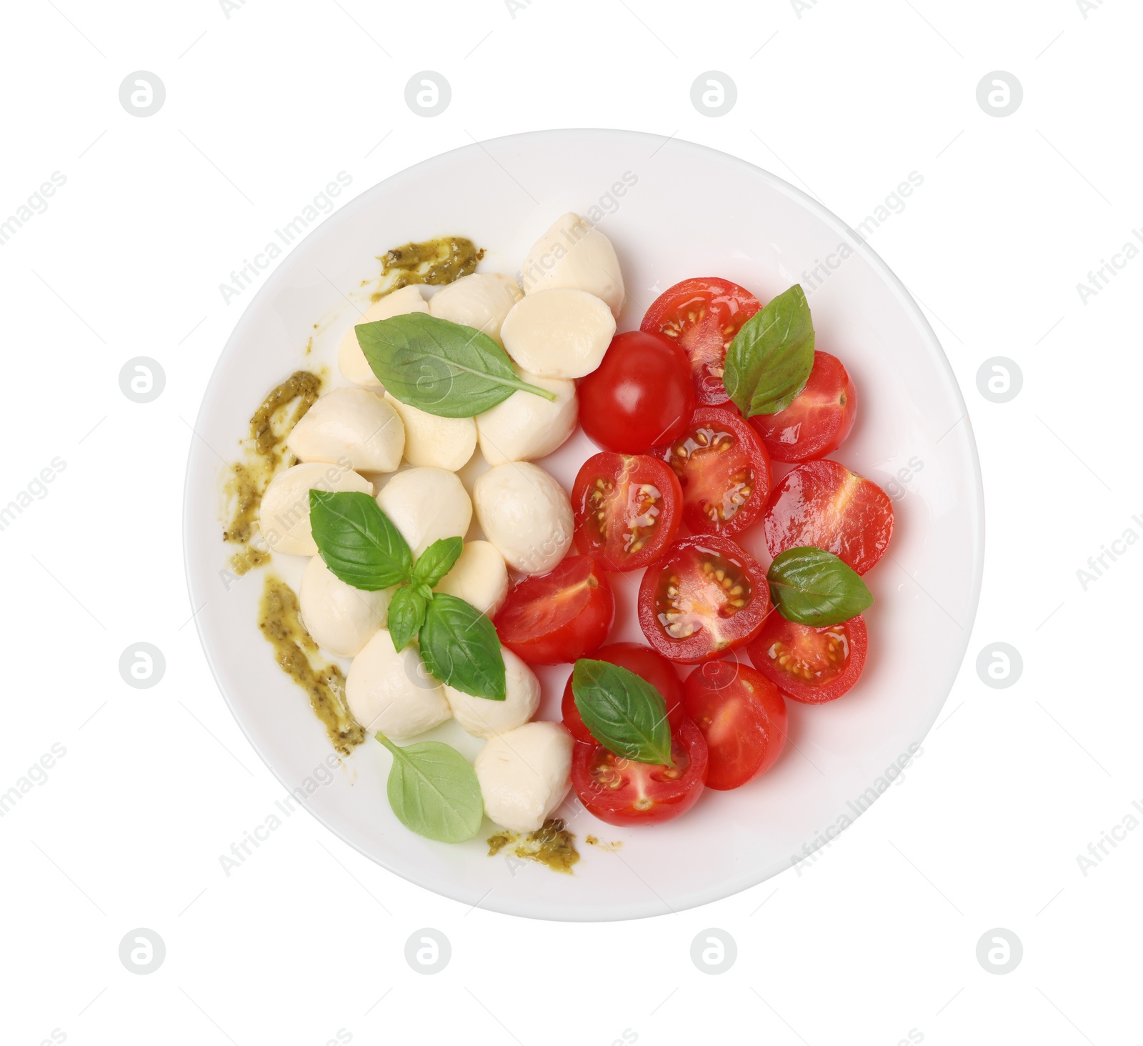 Photo of Plate of tasty Caprese salad with mozzarella, tomatoes, basil and pesto sauce isolated on white, top view