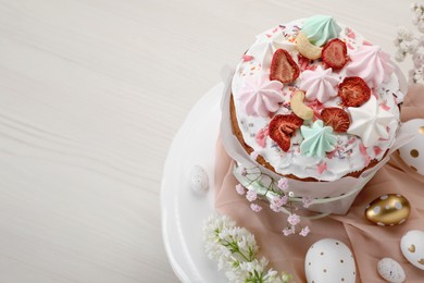 Photo of Traditional Easter cake with meringues and painted eggs on white wooden table, space for text