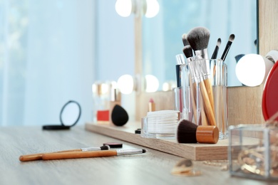 Photo of Organizer with cosmetic products for makeup on table near mirror. Space for text