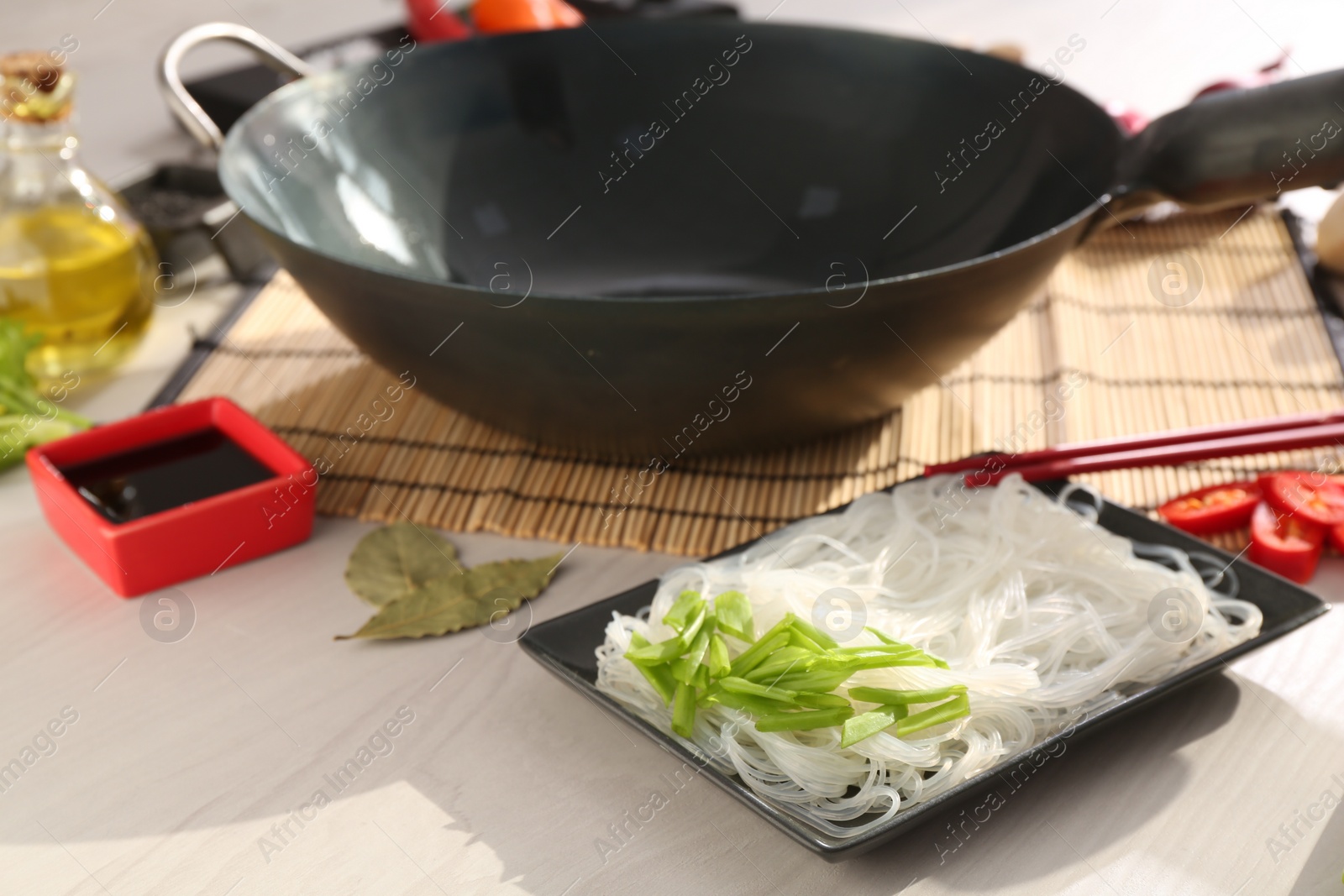 Photo of Wok and different products on white wooden table, closeup