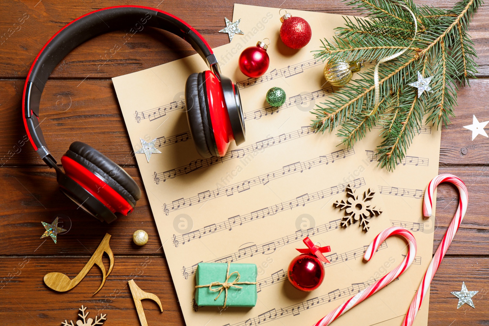 Photo of Flat lay composition with Christmas decorations, headphones and music sheets on wooden table