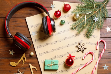 Photo of Flat lay composition with Christmas decorations, headphones and music sheets on wooden table