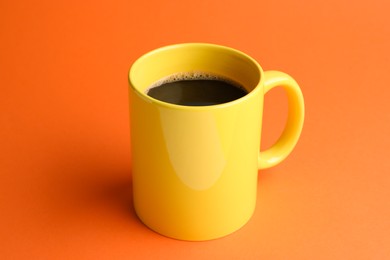 Photo of Yellow mug of freshly brewed hot coffee on orange background