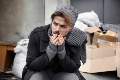 Poor young man sitting near garbage at dump