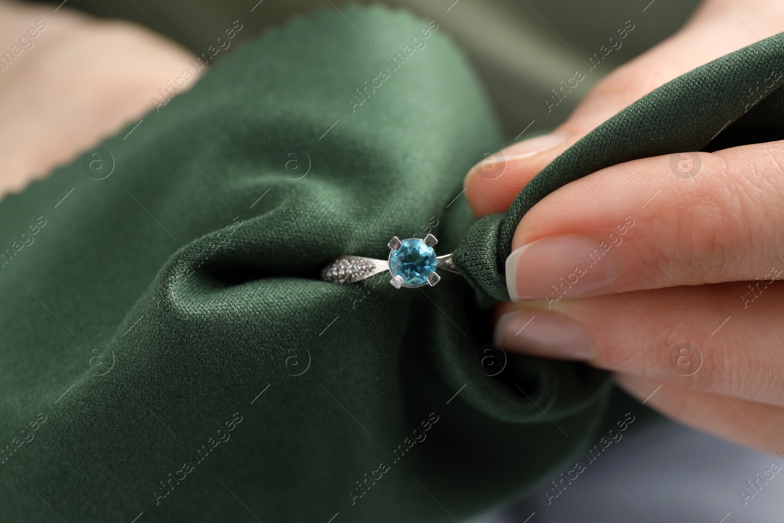 Photo of Jeweler cleaning topaz ring with microfiber cloth, closeup