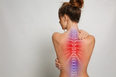 Image of Woman suffering from pain in back on light background, space for text
