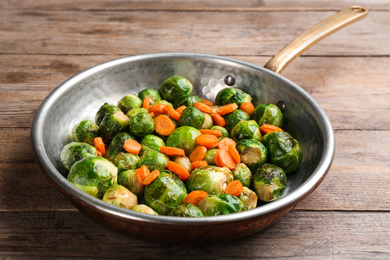 Roasted Brussels sprouts with carrot in frying pan on wooden table