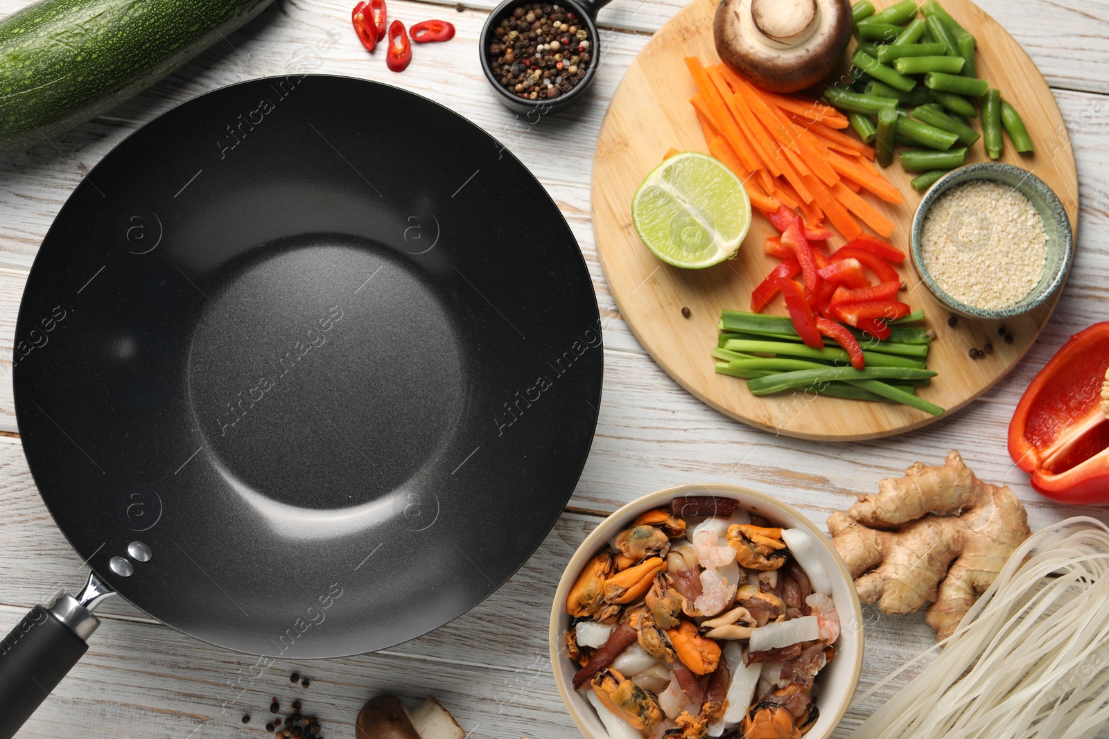 Photo of Flat lay composition with black wok and products on light wooden table