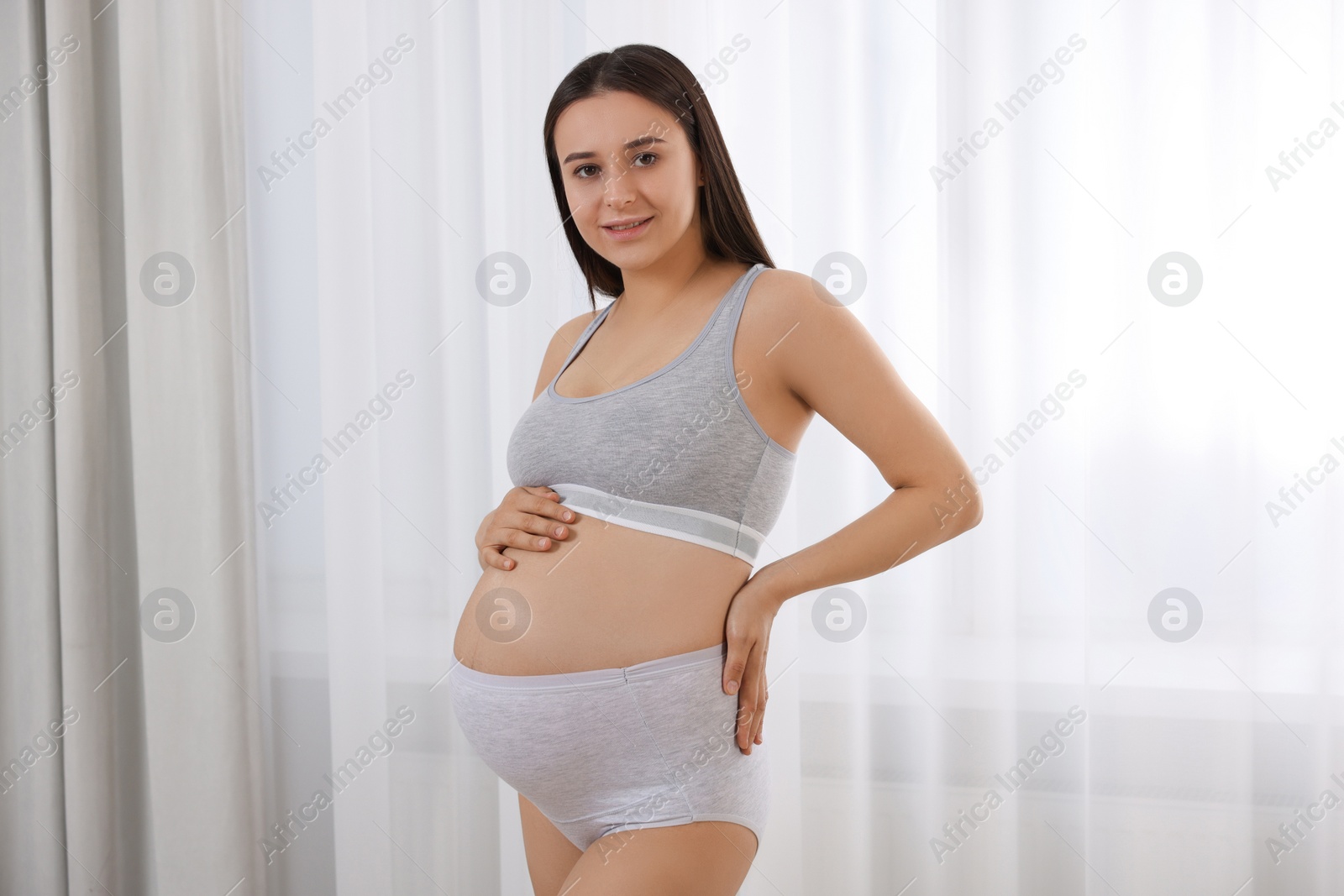 Photo of Beautiful pregnant woman in comfortable maternity underwear indoors