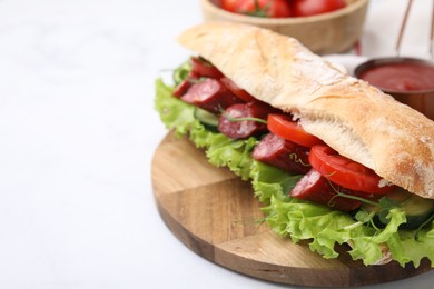 Delicious sandwich with sausages and vegetables on white table, closeup. Space for text