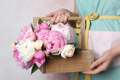 Woman with beautiful peonies on pink background, closeup