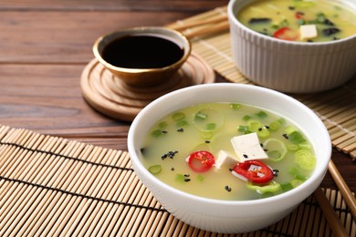 Photo of Bowls of delicious miso soup with tofu served on wooden table. Space for text