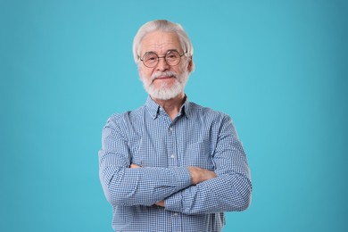 Portrait of stylish grandpa with glasses on light blue background