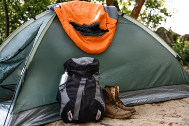 Camping tent with sleeping bag, boots and backpack on beach