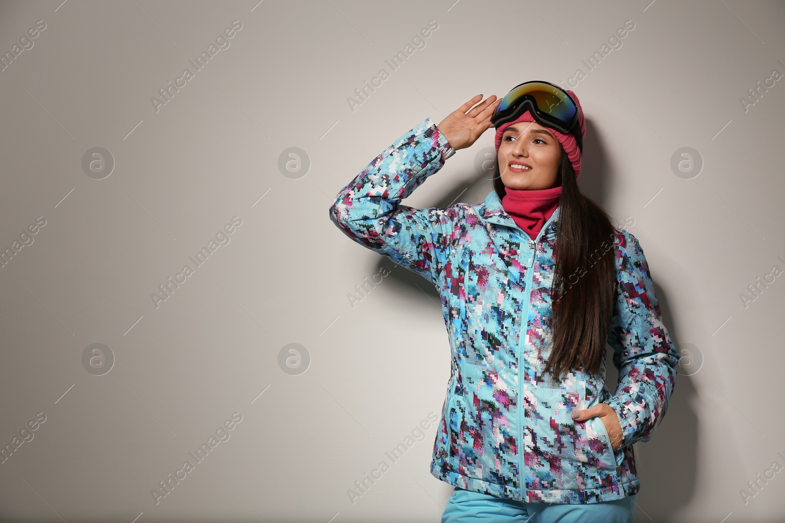 Photo of Woman wearing stylish winter sport clothes on light grey background, space for text