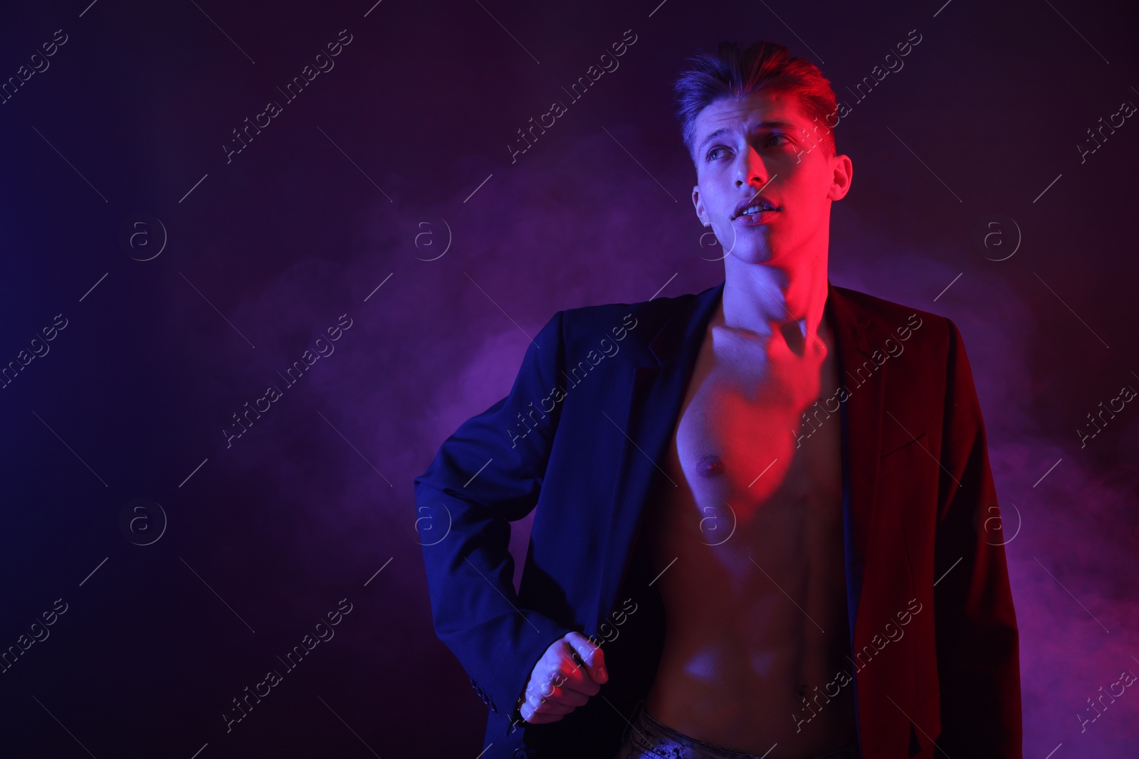 Photo of Sexy young man in neon lights with smoke effect. Space for text