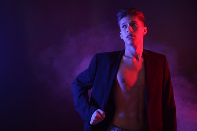 Sexy young man in neon lights with smoke effect. Space for text