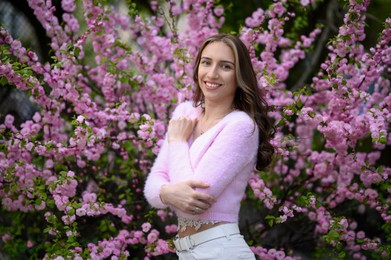 Photo of Beautiful young woman near blossoming sakura tree on spring day