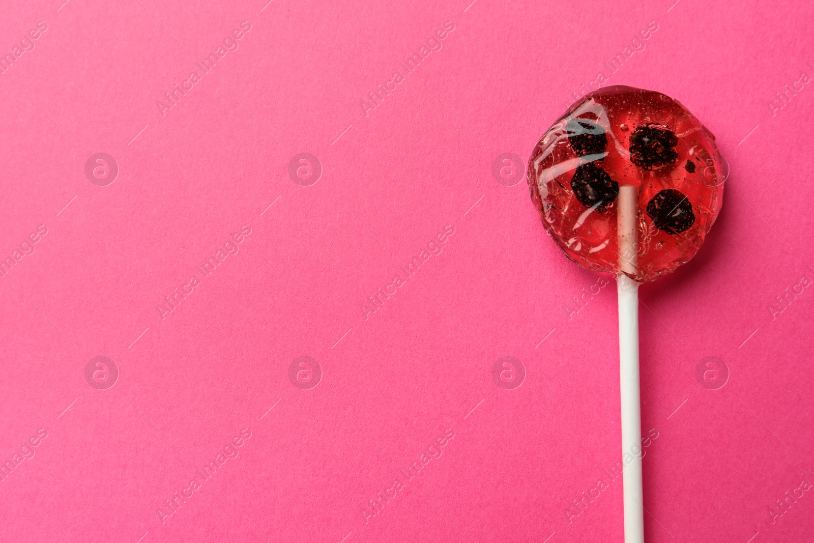 Photo of Sweet colorful lollipop with berries on pink background, top view. Space for text