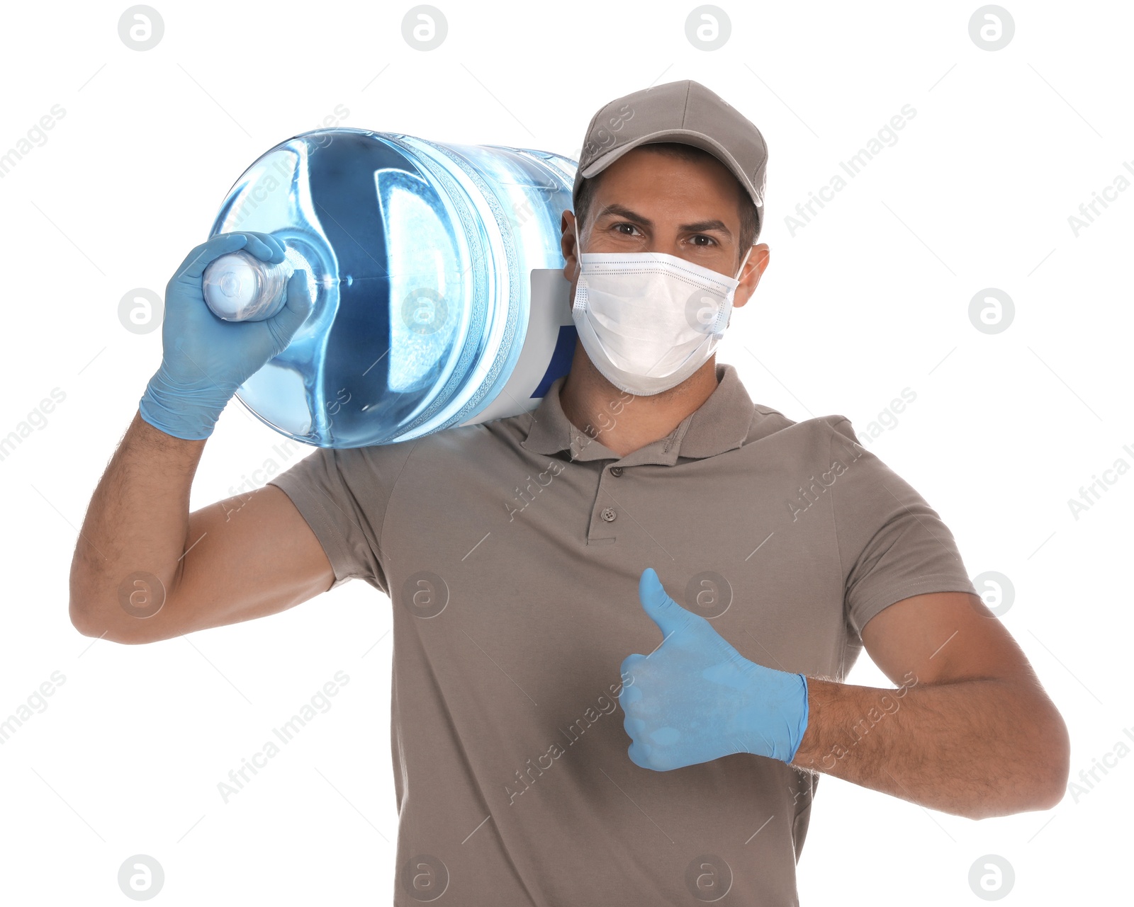 Photo of Courier in medical mask with bottle for water cooler showing thumb up on white background. Delivery during coronavirus quarantine