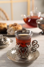 Glass of traditional Turkish tea in vintage holder on white wooden table