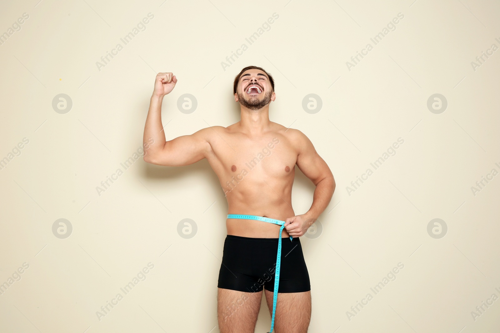 Photo of Fit man measuring his waist on color background. Weight loss