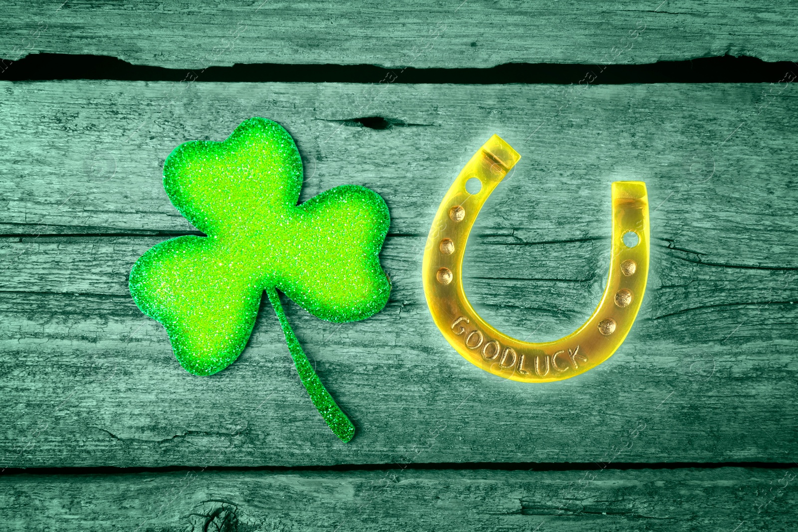 Image of St. Patrick's day. Decorative clover leaf and golden horseshoe on green wooden background, flat lay