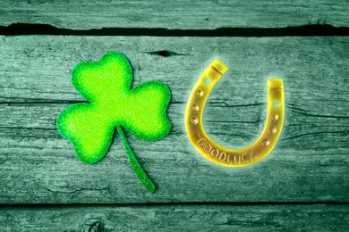 St. Patrick's day. Decorative clover leaf and golden horseshoe on green wooden background, flat lay