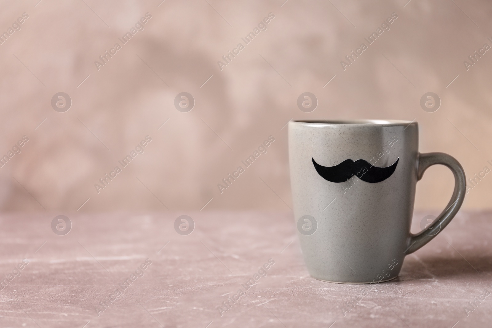 Photo of Cup with funny moustache on table. Father's day celebration