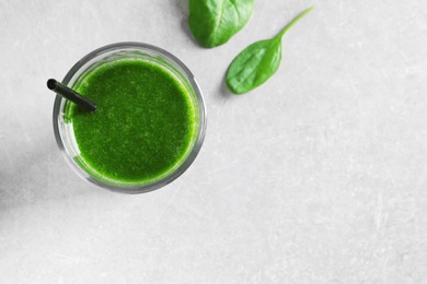 Glass with delicious detox juice and spinach on light background, top view