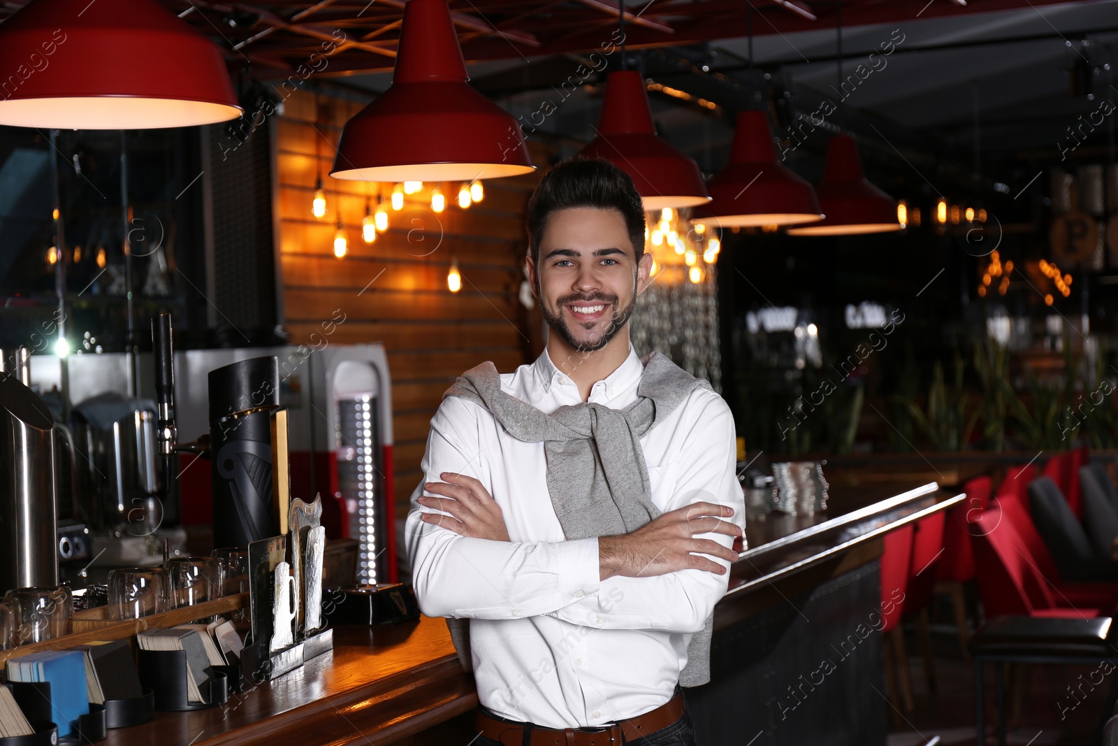 Photo of Young business owner standing near counter in his cafe