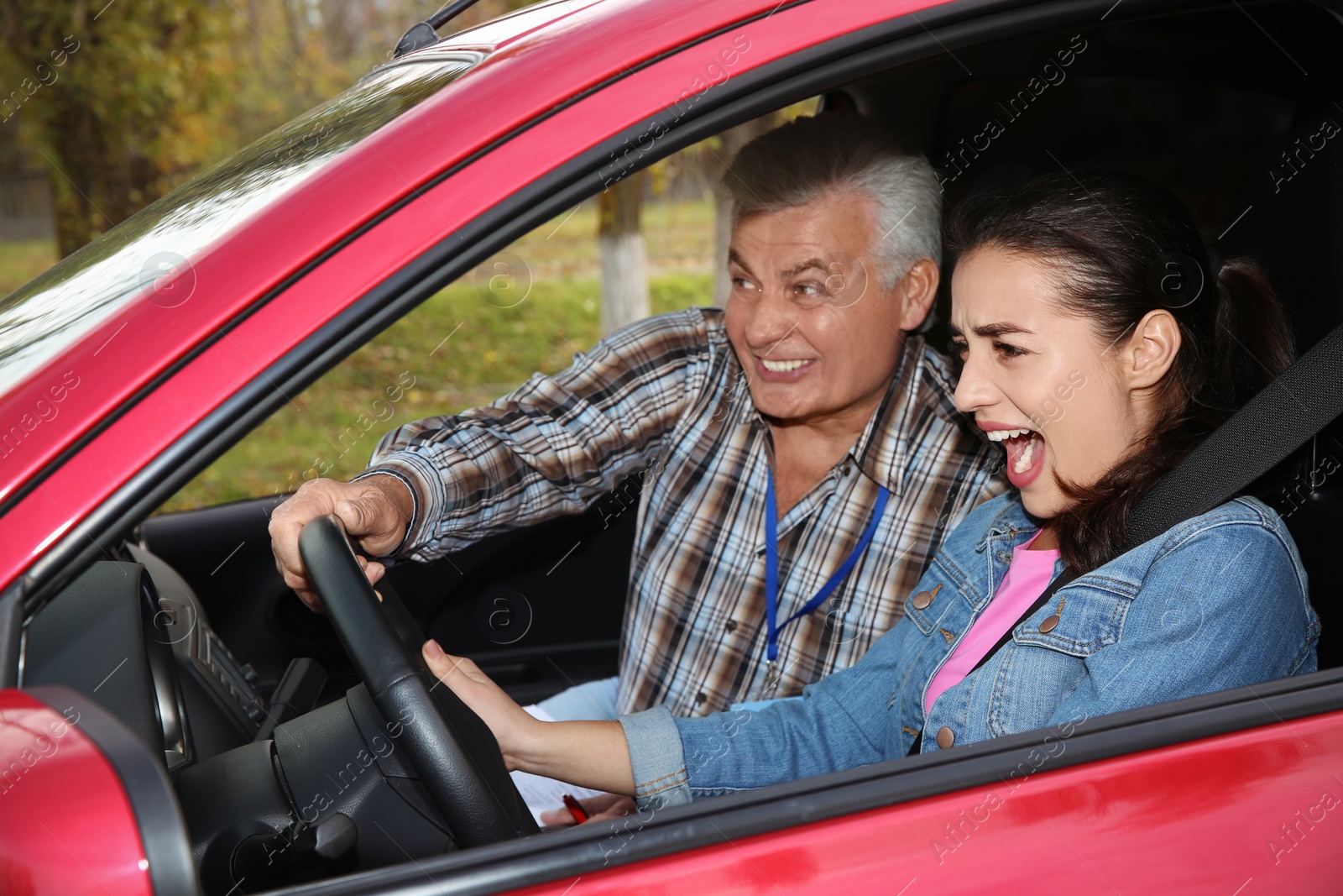 Photo of Young woman and senior instructor in car. Fail driving license exam