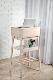 High wooden table with laptop as stand up workplace in modern interior