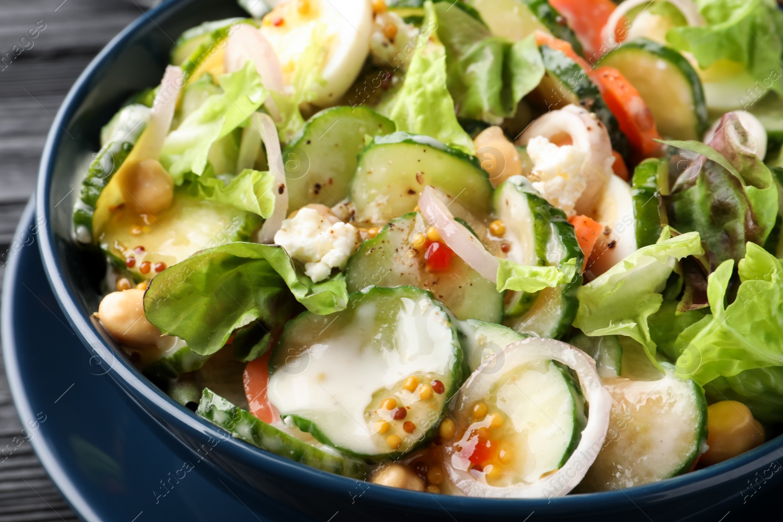 Photo of Bowl of delicious cucumber salad on table, closeup