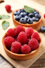 Photo of Tartlet with fresh raspberries on table, closeup. Delicious dessert